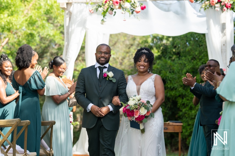 Joyful Couple Walks Down the Aisle Together During an Outdoor Wedding Ceremony Surrounded by Friends and Family in a Lush Garden After Their Vows