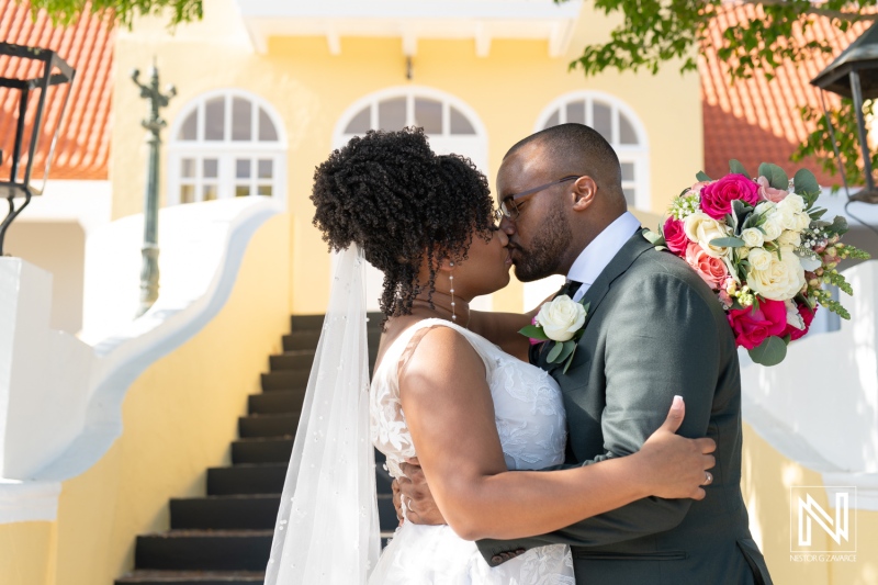 A Romantic Couple Shares a Kiss During Their Wedding Ceremony in a Scenic Outdoor Setting on a Sunny Day With Vibrant Flowers