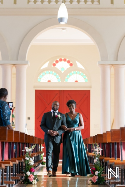 Elegant Couple Walking Down the Aisle in a Beautifully Decorated Chapel With an Eye-Catching Red Door, Celebrating a Special Occasion Amidst Floral Arrangements