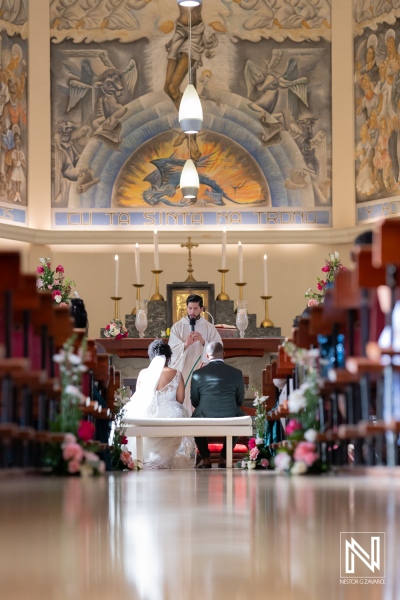 A Couple Exchanges Vows During a Wedding Ceremony Inside a Beautifully Adorned Church With Stunning Murals and Floral Decorations