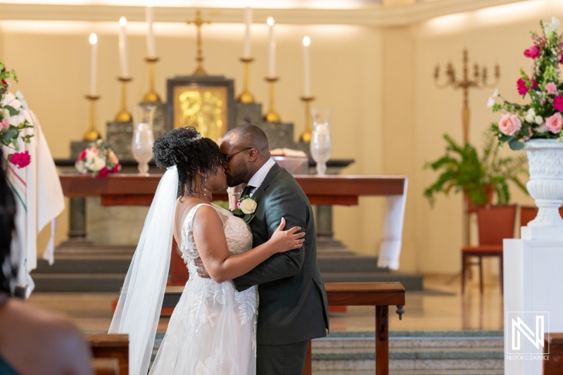 A Couple Exchanges a Kiss During Their Wedding Ceremony in a Beautifully Adorned Venue, Surrounded by Floral Arrangements and Flickering Candlelight