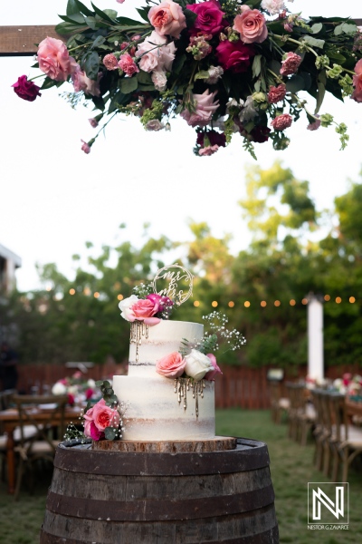 A Beautifully Decorated Wedding Cake Adorned With Fresh Flowers Sits on a Rustic Barrel in a Garden Setting, Capturing a Romantic Evening Atmosphere at an Outdoor Celebration