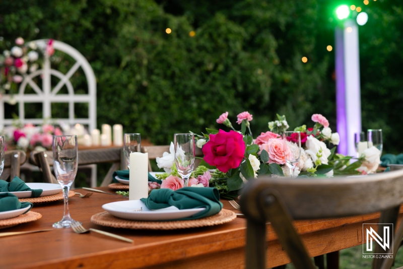 Elegant Outdoor Dining Setup Featuring Beautifully Arranged Floral Centerpieces With Colored Lights Illuminating the Evening Garden During a Festive Gathering