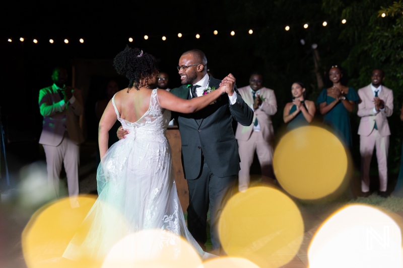 A Joyful Couple Dances Together Under String Lights at Their Wedding Reception, Surrounded by Cheerful Guests Celebrating Their Special Moment During an Evening Outdoor Event