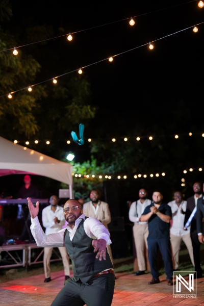 A Lively Outdoor Wedding Reception in the Evening Featuring a Joyful Dance Performance Under String Lights in a Charming Garden Setting