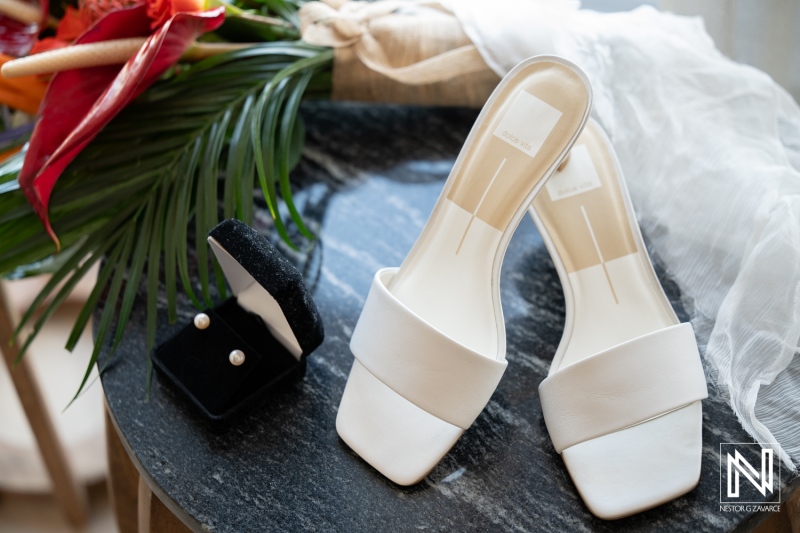 White wedding shoes and pearl earrings on a table at Avila Beach Hotel in Curacao before the wedding ceremony