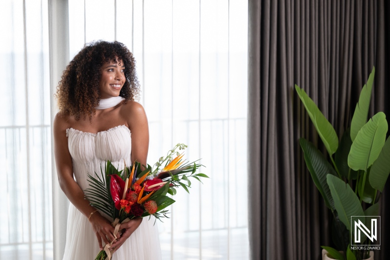 Bride prepares for wedding at Avila Beach Hotel in Curacao with a bouquet in hand and a smile on her face
