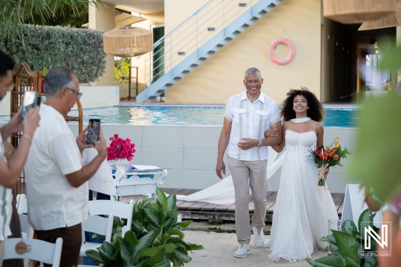 Wedding ceremony at Avila Beach Hotel in Curacao takes place by the pool with guests and family enjoying the moment