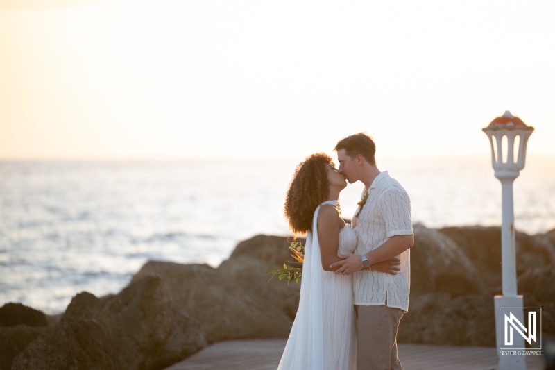 Couple shares a kiss during their wedding ceremony at Avila Beach Hotel in Curacao during sunset