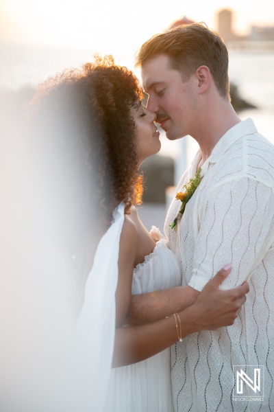Couple shares a kiss during their wedding ceremony at Avila Beach Hotel in Curacao at sunset near the water