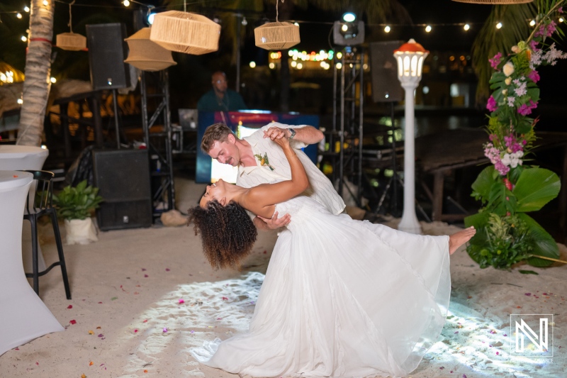 Couple shares a dance during their wedding celebration at Avila Beach Hotel in Curacao by the ocean under bright lights