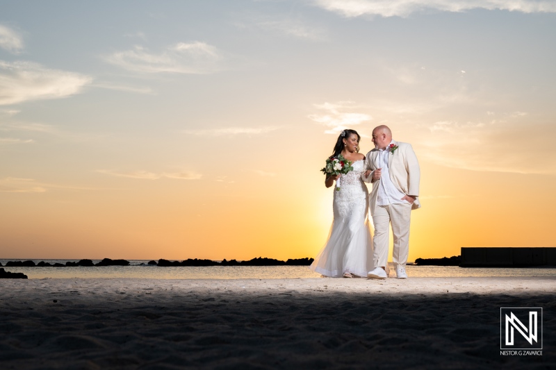 Couple walks hand in hand on the beach during their wedding ceremony at Sunscape Curacao Resort with a stunning sunset backdrop