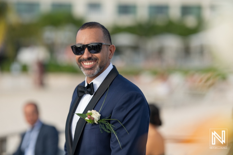 Groom smiles confidently during a wedding ceremony at Curacao Marriott Beach Resort as the sun sets over the horizon