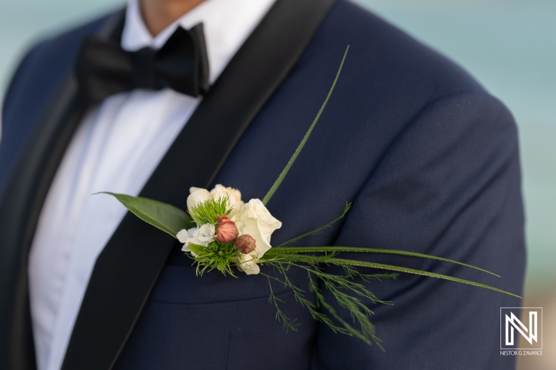 Elegant groom's attire featuring a delicate boutonniere at a wedding in Curacao Marriott Beach Resort during sunset overlooking the ocean