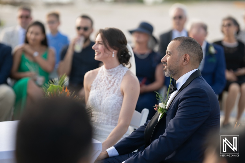 Beautiful wedding ceremony at sunset on the beach in Curacao Marriott Beach Resort with happy couple and guests celebrating love