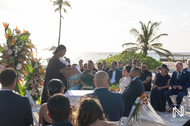 Beautiful wedding ceremony taking place at Curacao Marriott Beach Resort during sunset with guests enjoying the view and tropical backdrop