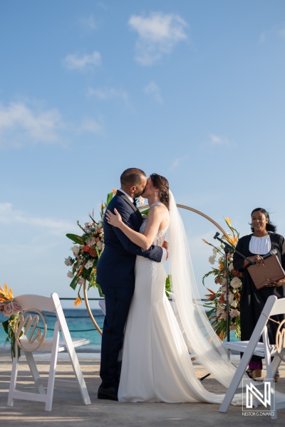 Couple shares a romantic kiss during their wedding ceremony at Curacao Marriott Beach Resort as the sun sets over the horizon