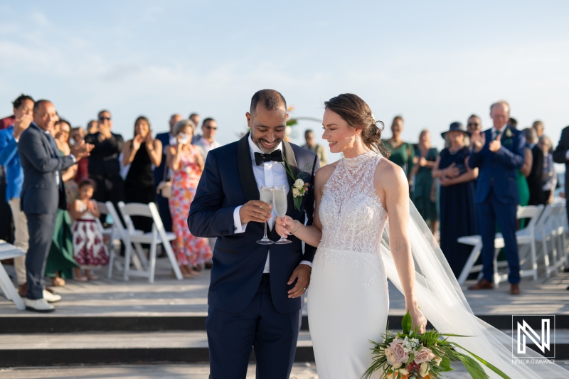 Couple celebrating their wedding at sunset in Curacao with beautiful beach backdrop and joyful guests in attendance