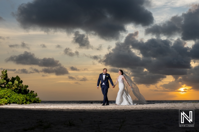 Romantic sunset wedding at Curacao Marriott Beach Resort with bride and groom walking hand in hand on the beach