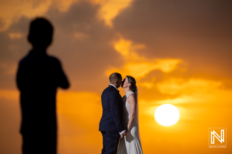 Romantic sunset wedding ceremony at Curacao Marriott Beach Resort with a couple sharing a kiss amidst a stunning backdrop