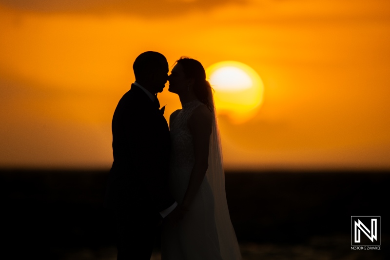 Couple shares a tender moment against a stunning sunset at Curacao Marriott Beach Resort during their wedding ceremony