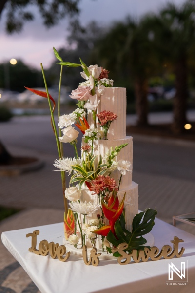 Stunning wedding cake adorned with fresh flowers at a sunset wedding in Curacao Marriott Beach Resort