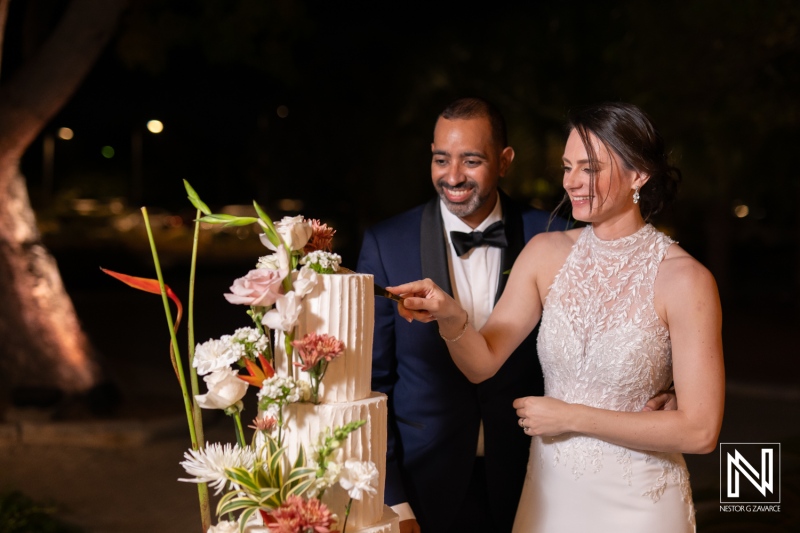 Couple joyfully shares their wedding cake moment at a beautiful sunset ceremony in Curacao Marriott Beach Resort