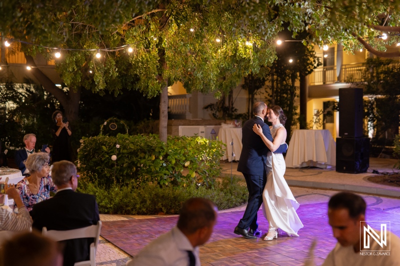 Couple shares their first dance under twinkling lights at a beautiful sunset wedding celebration in Curacao Marriott Beach Resort