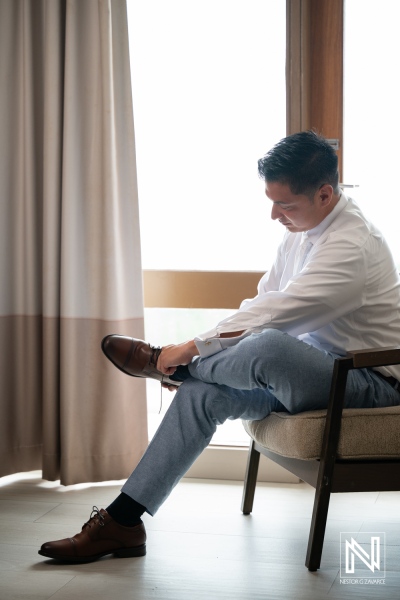 Groom prepares for wedding at Dreams Curacao Resort with ocean view in the background