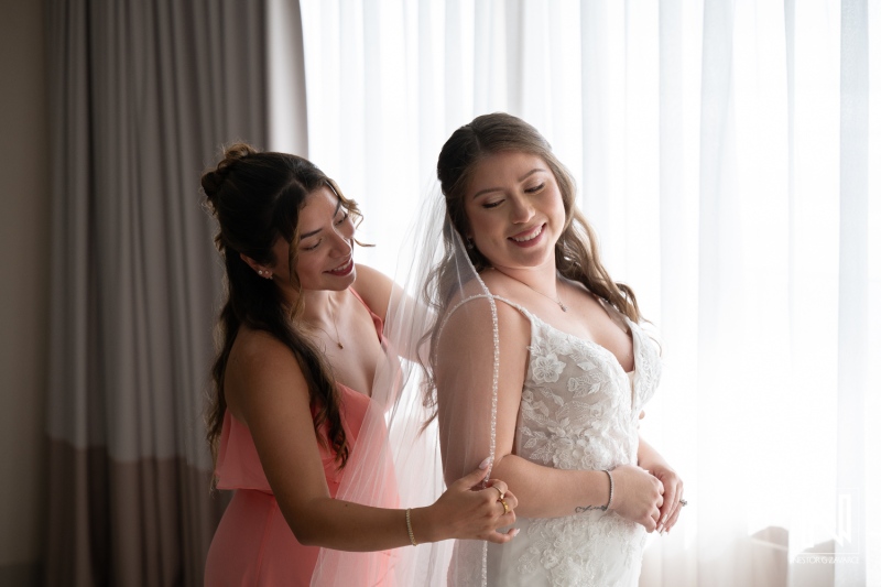 Bridesmaid helps bride prepare for wedding ceremony at Dreams Curacao Resort in Curacao during daytime
