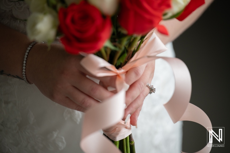 Wedding ceremony at Dreams Curacao Resort focuses on the bride holding a bouquet with red roses before the big moment
