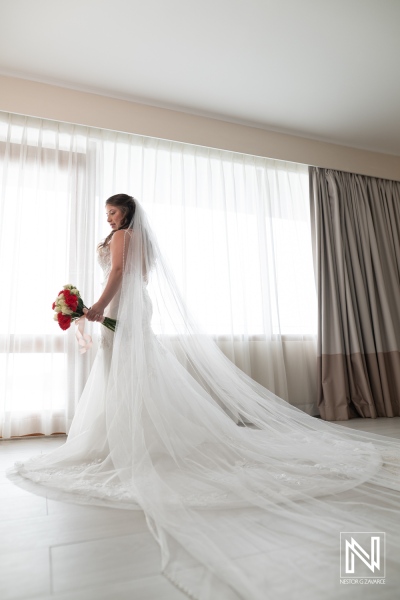 Beautiful bride stands by window at wedding ceremony in Dreams Curacao Resort