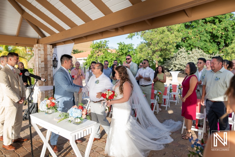 Wedding ceremony at Dreams Curacao Resort with guests witnessing vows exchanged by the couple at sunset