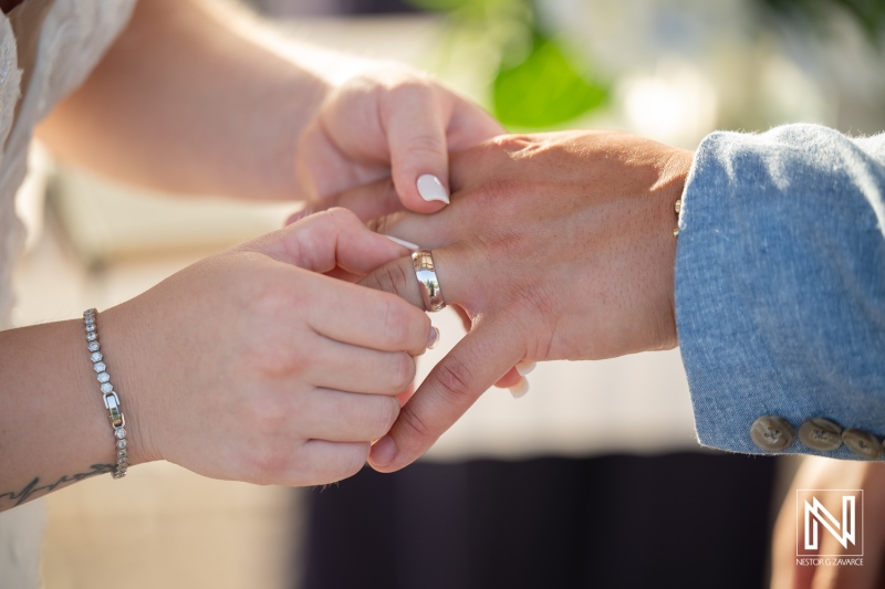 Couple exchanging wedding rings during ceremony at Dreams Curacao Resort in Curacao on a sunny day