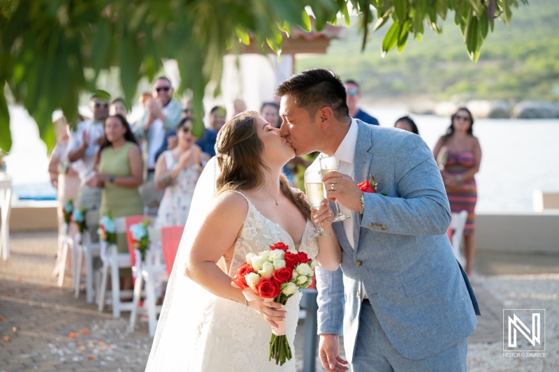 Couple shares a kiss after wedding ceremony at Dreams Curacao Resort during sunset