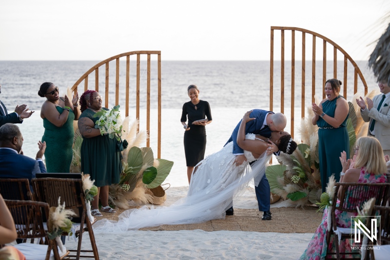 Couple shares kiss during wedding ceremony at Renaissance Wind Creek in Curacao by the ocean