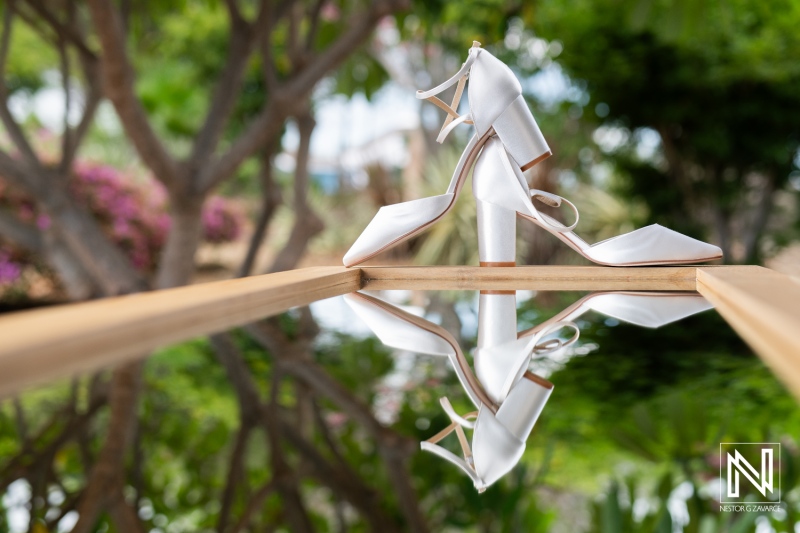 Beautiful white wedding shoes reflect on a wooden surface at Papagayo Beach Resort in Curacao, just before a wedding celebration begins