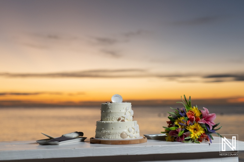 Celebration of love with a stunning wedding cake and vibrant bouquet at sunset in Curacao