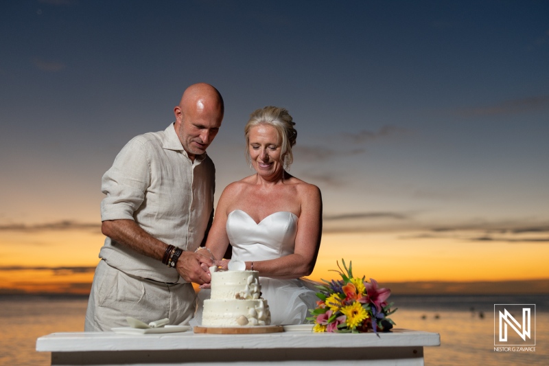 Couple cuts wedding cake on beach during sunset in Curacao at Karakter venue