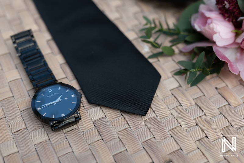 Elegant wedding accessories displayed at Avila Beach Hotel in Curacao with a stylish watch and black tie ready for the special occasion