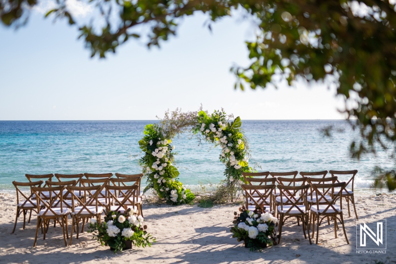 Beautiful wedding setup at Playa Hunku in Curacao with a floral arch and empty chairs arranged for the ceremony by the beach