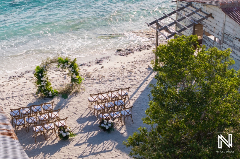 Dreamy beach wedding setup at Playa Hunku in Curacao with floral arrangements and wooden chairs