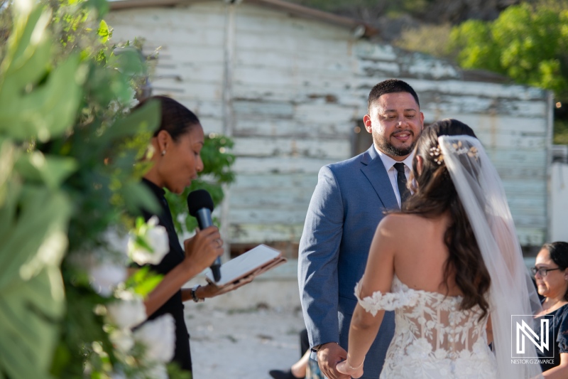 Couple exchanges vows during a romantic wedding ceremony at Playa Hunku in Curacao surrounded by lush greenery and personal touches