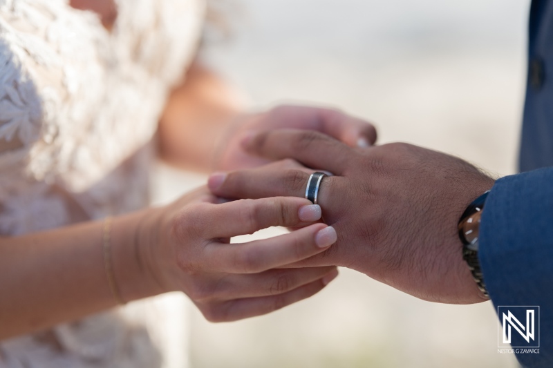 Wedding ceremony at Playa Hunku, Curacao, captures the moment of exchanging wedding rings in a beautiful tropical setting