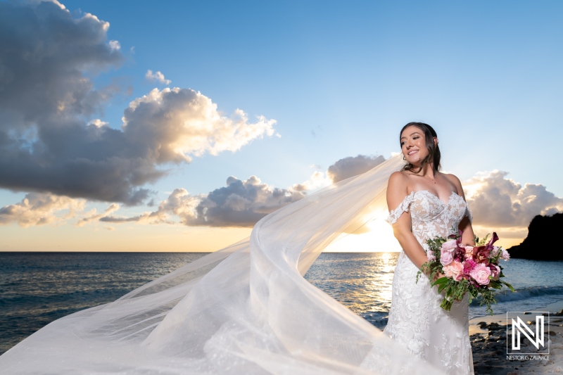 Beautiful bride at Playa Hunku in Curacao celebrates her wedding with a stunning sunset backdrop and flowing veil