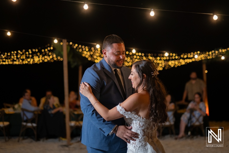 Couple shares a romantic dance under twinkling lights at their wedding celebration on Playa Hunku in Curacao