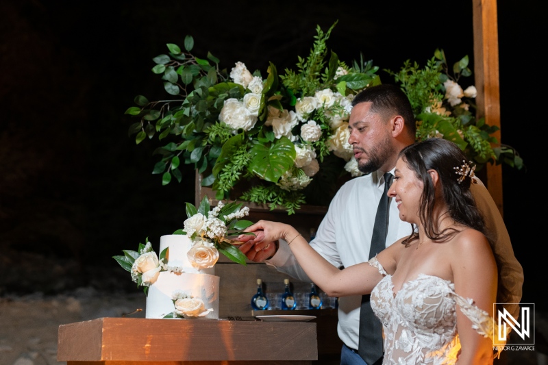 Couple cuts their wedding cake at Playa Hunku in Curacao during a beautiful beach ceremony at night