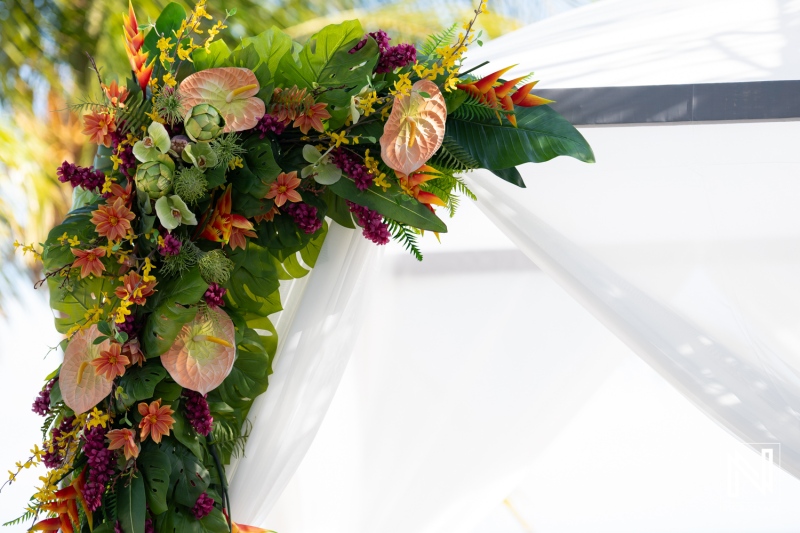 Colorful Floral Arrangement Enhances a Wedding Backdrop at a Tropical Venue, Featuring Vibrant Foliage and Seasonal Blooms on a Sunny Day