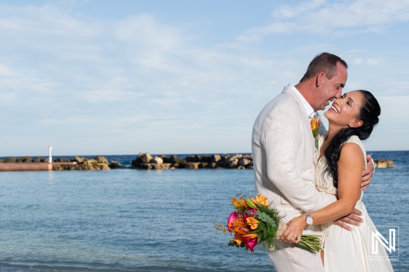 Couple Celebrates Their Beach Wedding With Joyful Smiles and a Colorful Bouquet, Enjoying a Romantic Moment by the Serene Ocean at Sunset