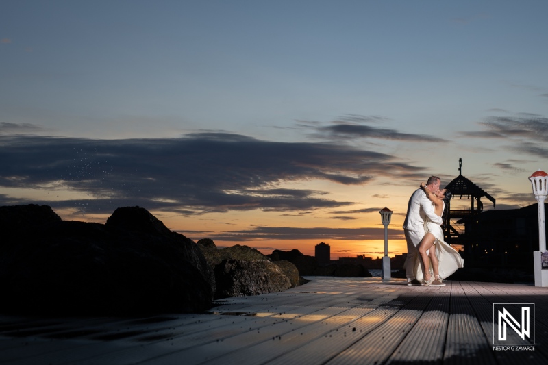 Couple Dances Romantically on a Wooden Pier During Sunset, Surrounded by Scenic Clouds and an Elegant Backdrop of the Ocean